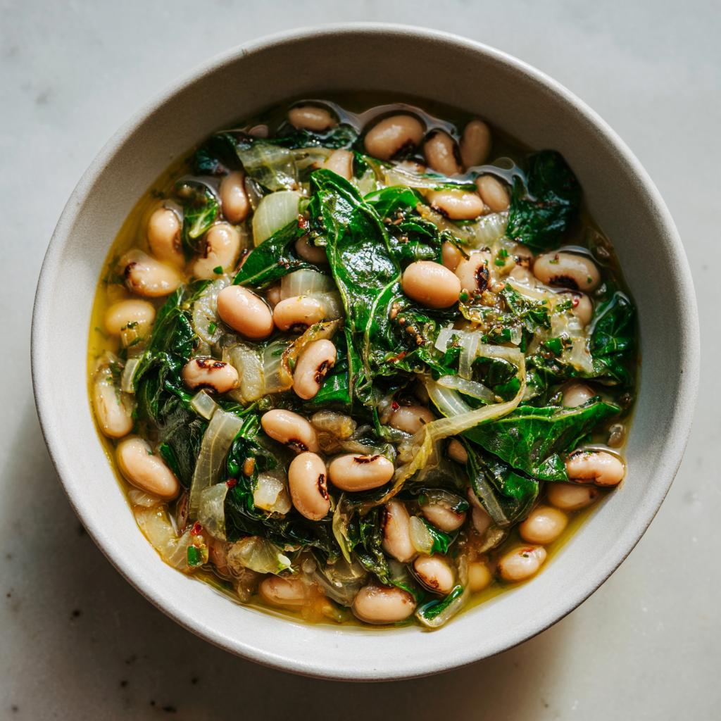 Close-up of a bowl filled with blackeyed peas and wilted greens, a comforting dish from blackeyed pea recipes.