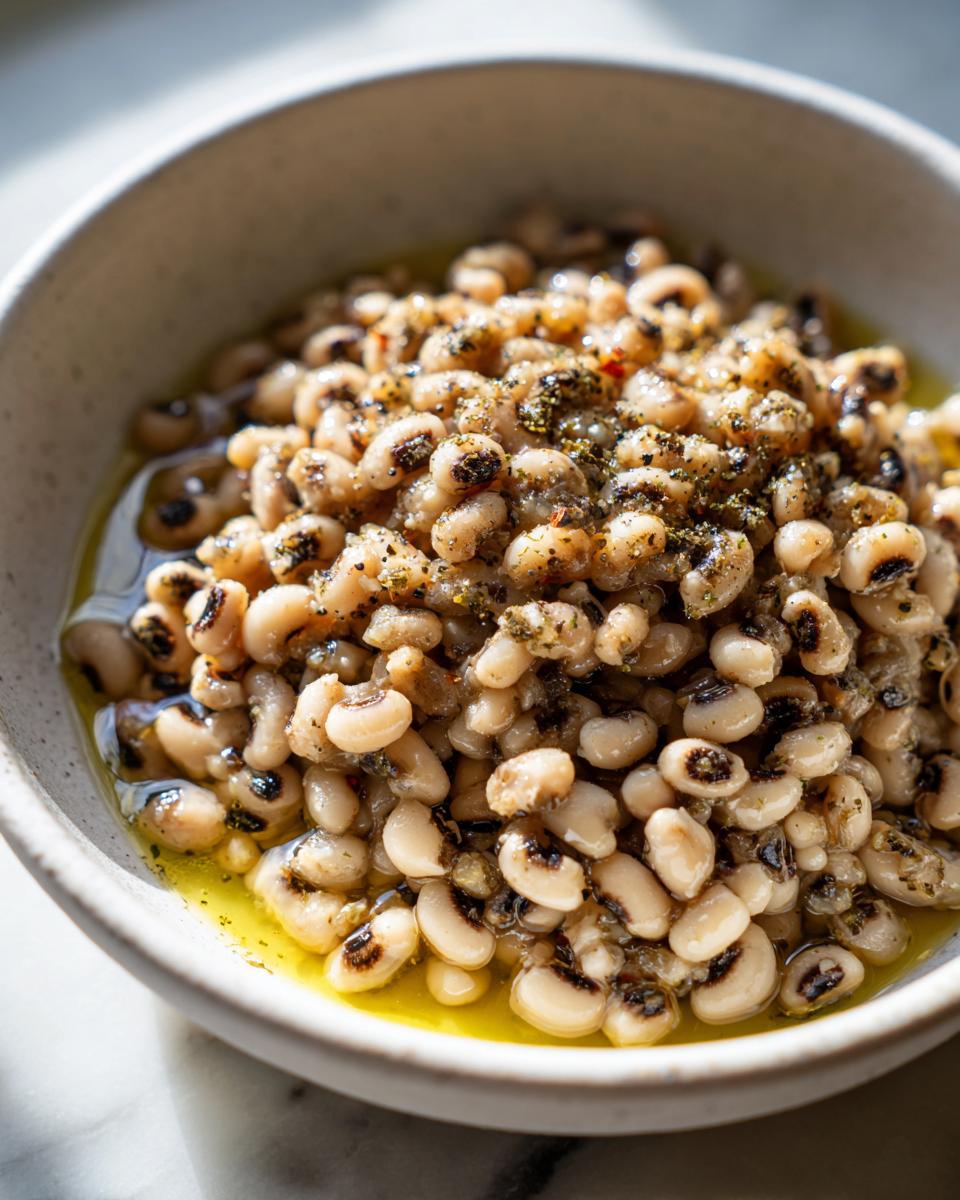 Close-up of creamy black eyed peas seasoned with herbs and spices in a rustic bowl.