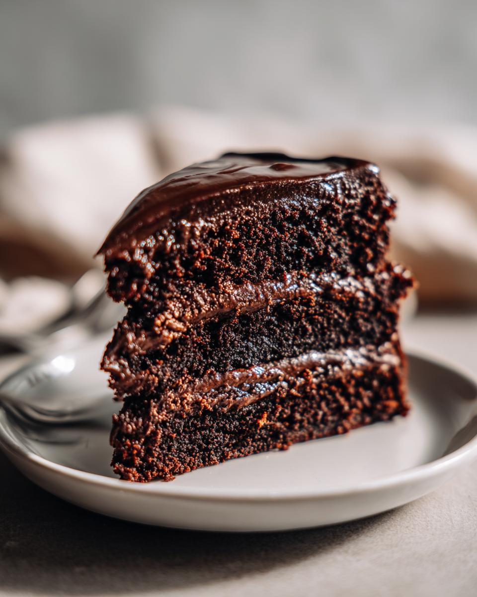 A decadent slice of moist chocolate cake with rich chocolate frosting, perfect for any occasion.