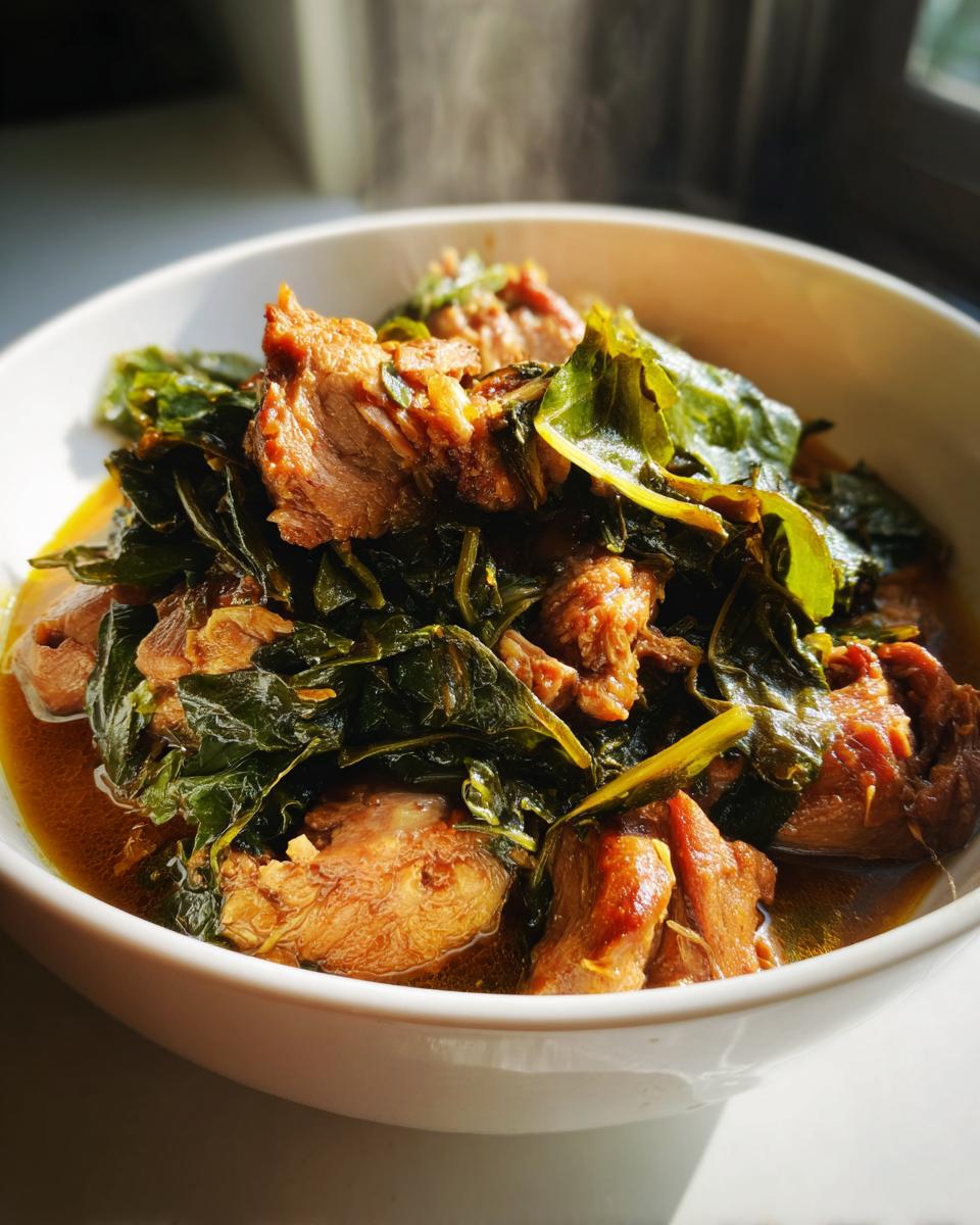 Close-up of a white bowl filled with tender pork and wilted greens, a perfect New Years Day Dinner.