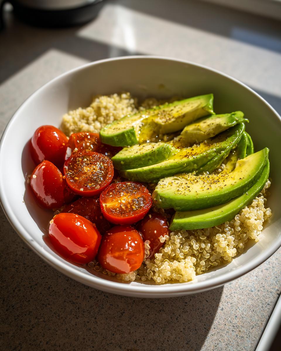 A vibrant quinoa bowl featuring sliced avocado, cherry tomatoes, and fluffy quinoa, showcasing a beautiful cooking aesthetic.