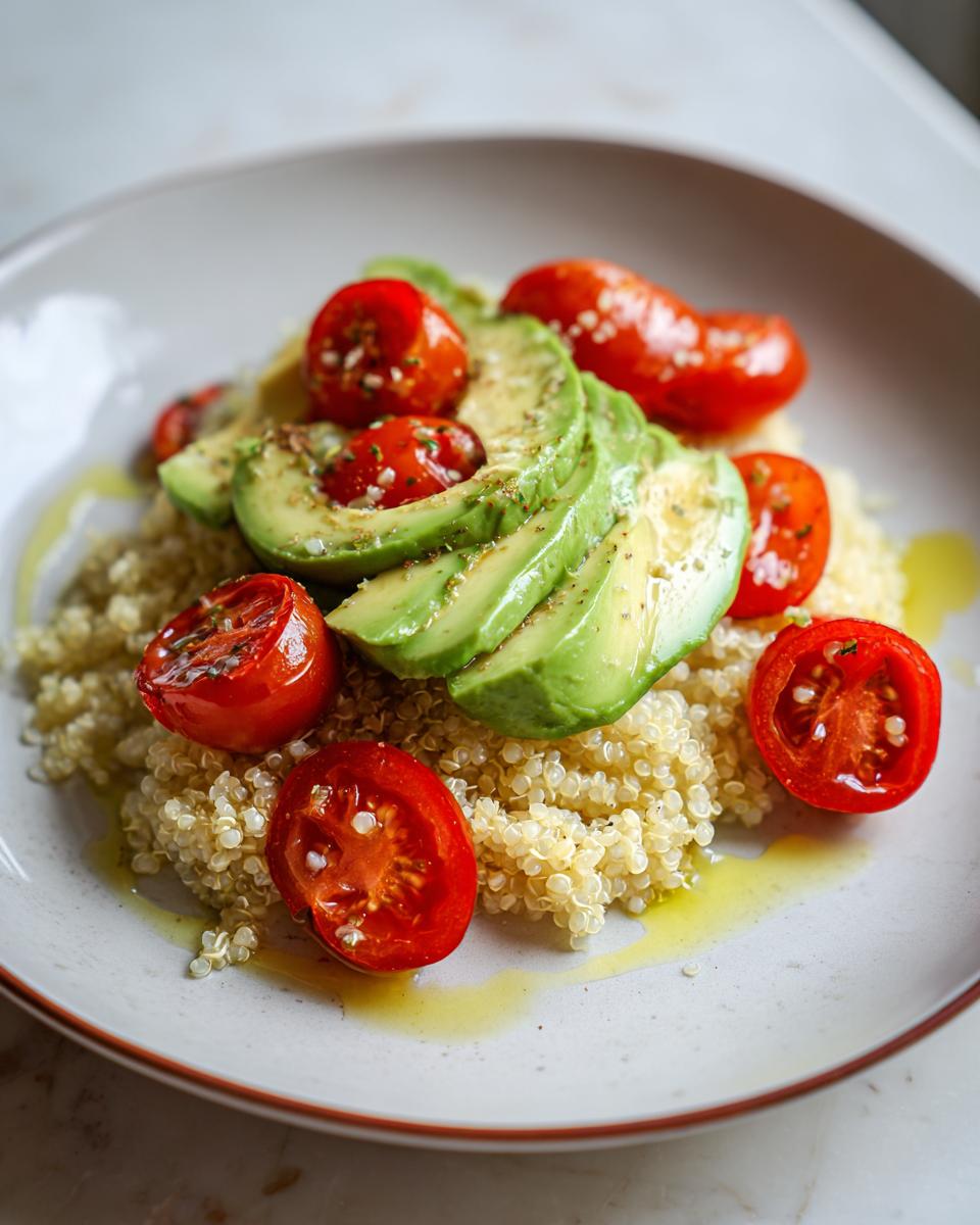 A beautiful quinoa bowl topped with sliced avocado and roasted cherry tomatoes, showcasing a vibrant cooking aesthetic.