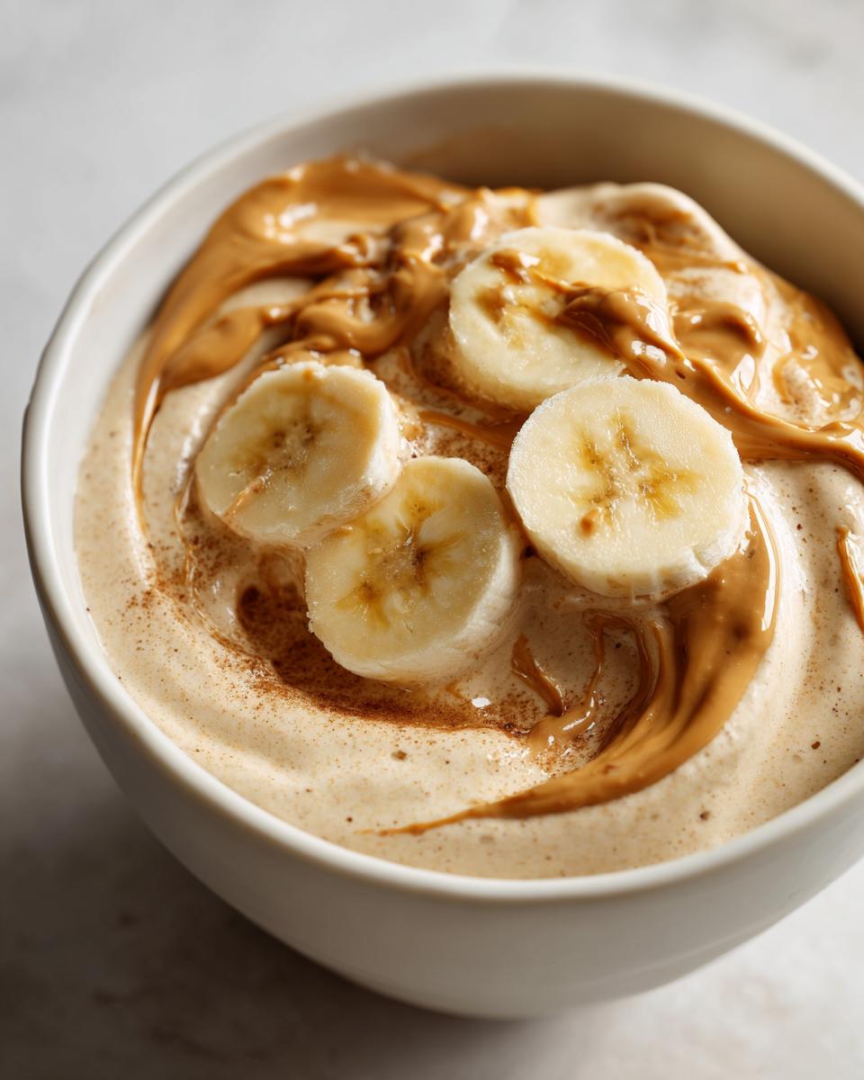 Bowl of banana nice cream topped with peanut butter swirl and banana slices