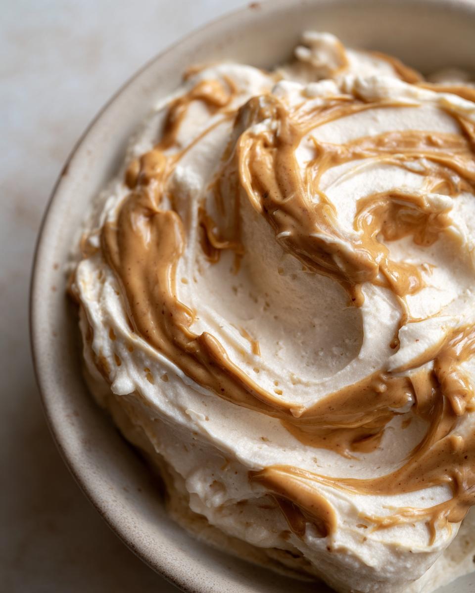 Close-up of creamy banana nice cream with swirls of peanut butter in a bowl