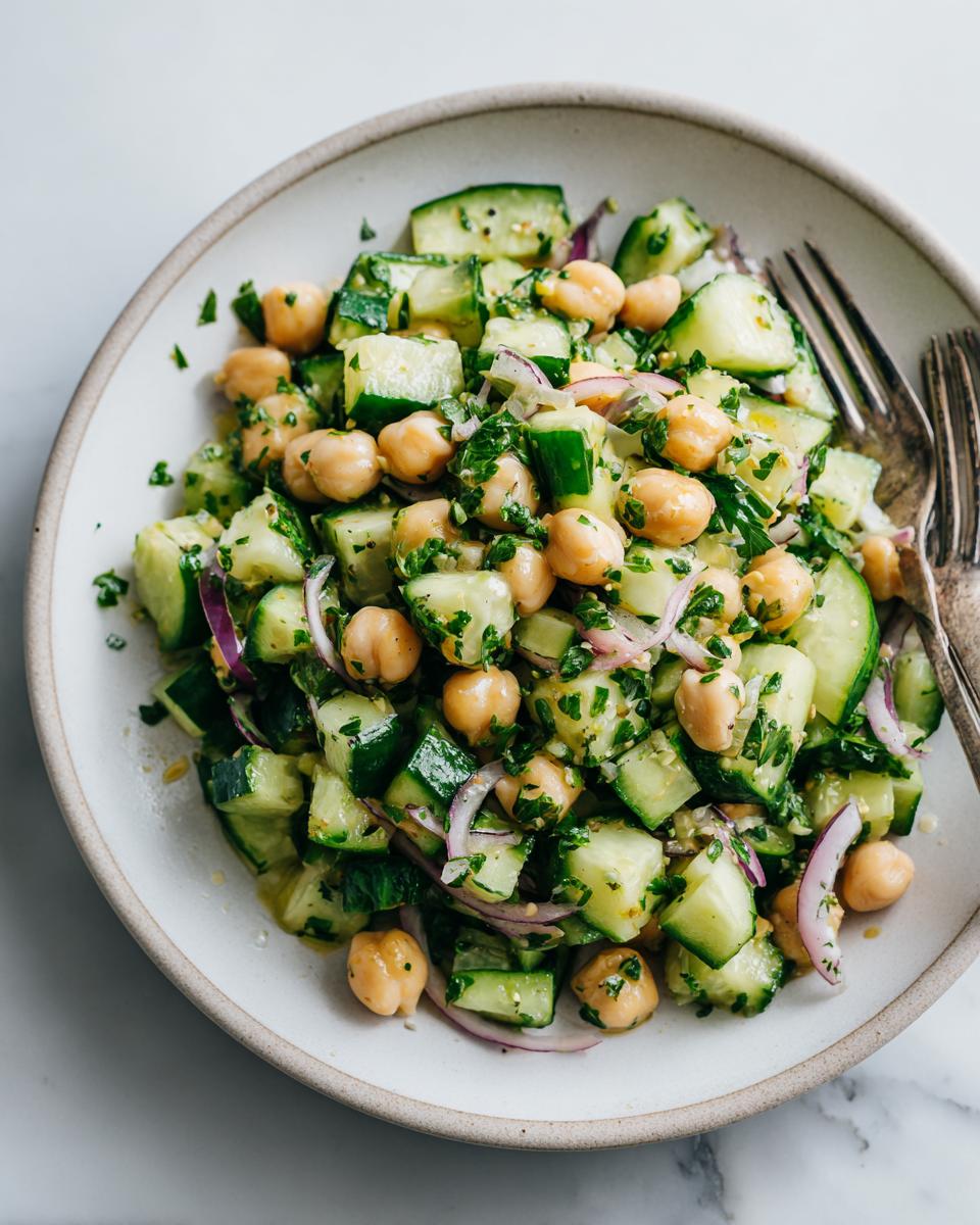 Bowl of chickpea and cucumber salad weight loss with parsley and red onion slices.