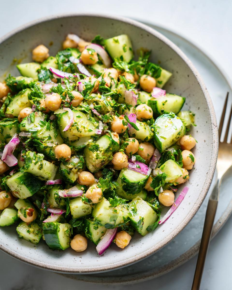 Bowl of chickpea and cucumber salad weight loss with chopped cucumbers, chickpeas, herbs, and red onions.