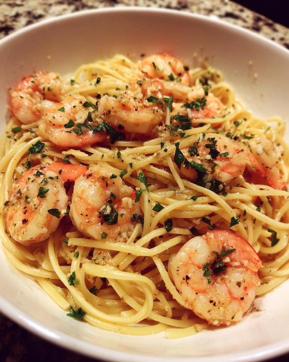 Close-up of garlic butter shrimp pasta with shrimp, spaghetti, and herbs in a white bowl
