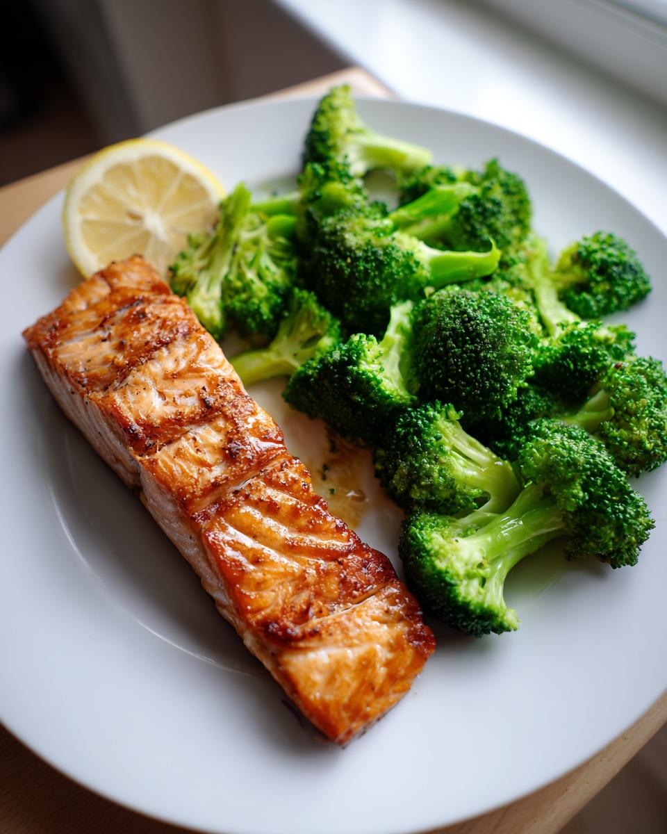 Plate with grilled salmon and steamed broccoli with a lemon slice on the side