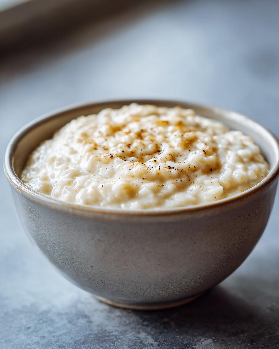 Close-up of a bowl filled with creamy homemade vanilla bean rice pudding dessert topped with cinnamon.
