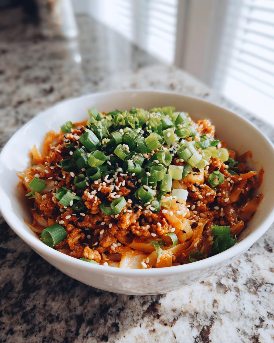 Bowl of low carb egg roll in a bowl recipe topped with chopped green onions and sesame seeds.