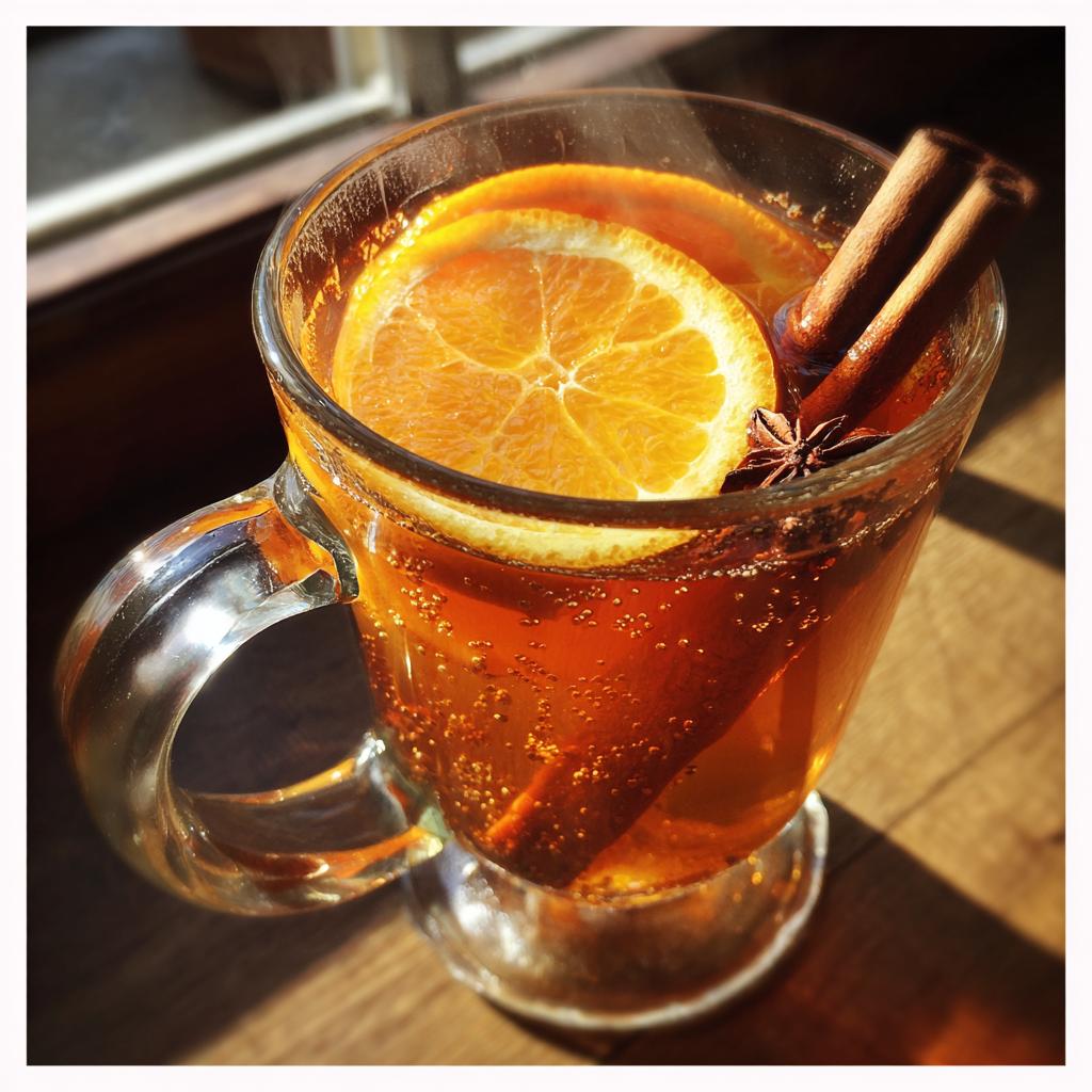 Glass mug of slow cooker mulled apple cider drink with orange slice, cinnamon sticks, and star anise