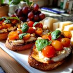 Toasted bruschetta topped with cherry tomatoes, basil, and cheese, served with grapes and cheese slices