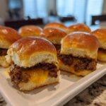 Plate of cheesy game day sliders with beef patties on soft buns.