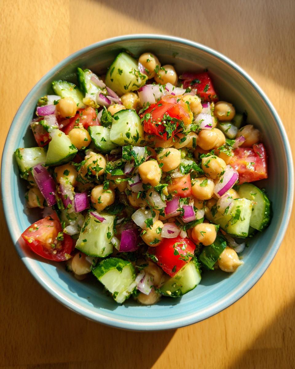 Colorful chickpea salad lunch for ramadan with cucumbers, tomatoes, onions, and herbs in a bowl.