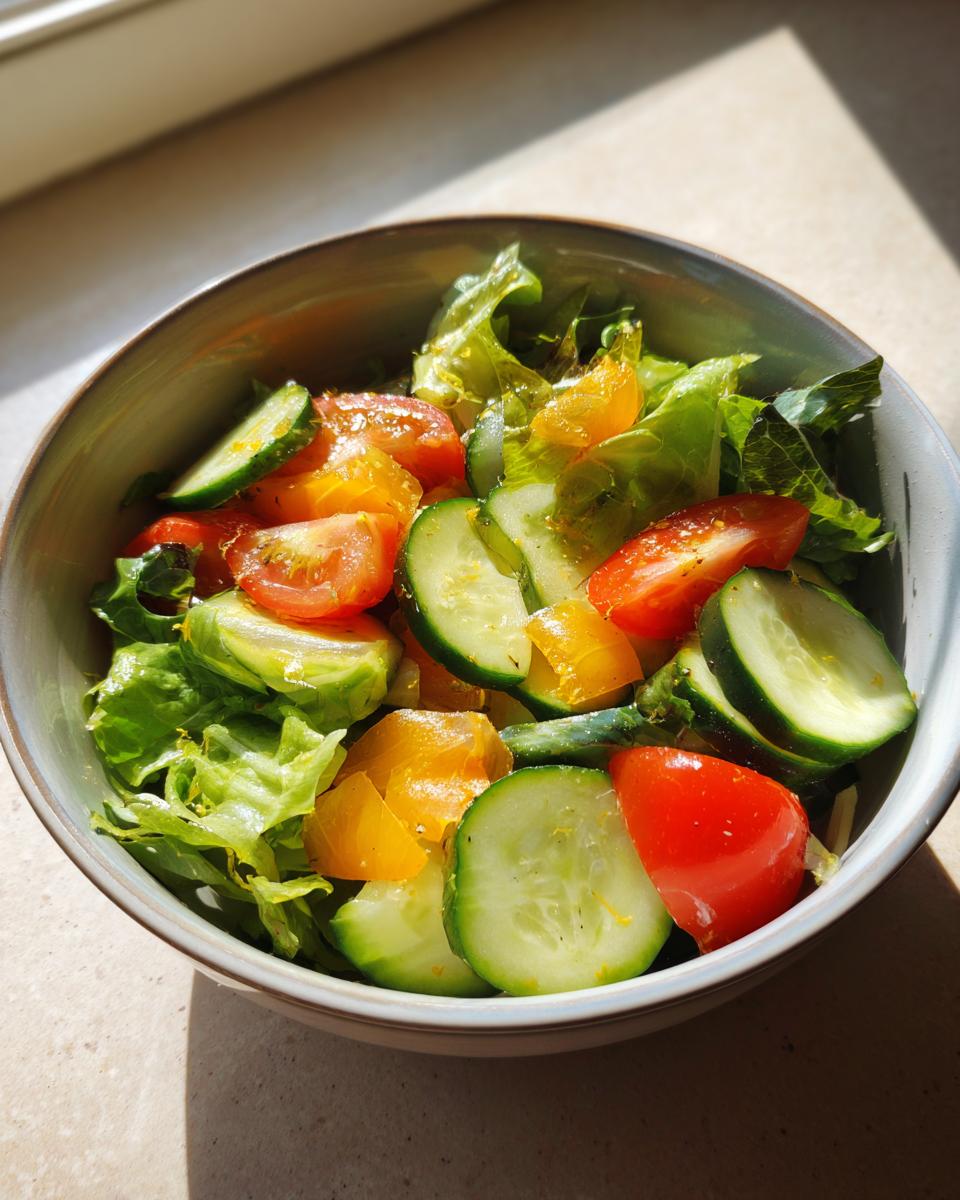 Bowl of fresh salad with lettuce, cucumber slices, cherry tomatoes, and yellow bell peppers for easy salad recipes