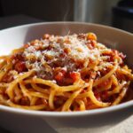 Bowl of steaming spaghetti topped with tomato sauce and grated cheese, representing one pot dinners
