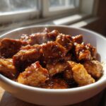 Steaming glazed chicken pieces in a white bowl, showcasing slow cooker recipes.