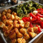 Sheet pan dinners with seasoned chicken, roasted broccoli, red bell peppers, and onions.