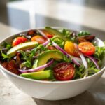 Bowl of fresh salad with avocado slices, cherry tomatoes, red onion, and mixed greens for light spring lunches.