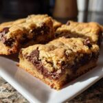 Close-up of chocolate chip blondie bars with gooey chocolate chips on a white plate.