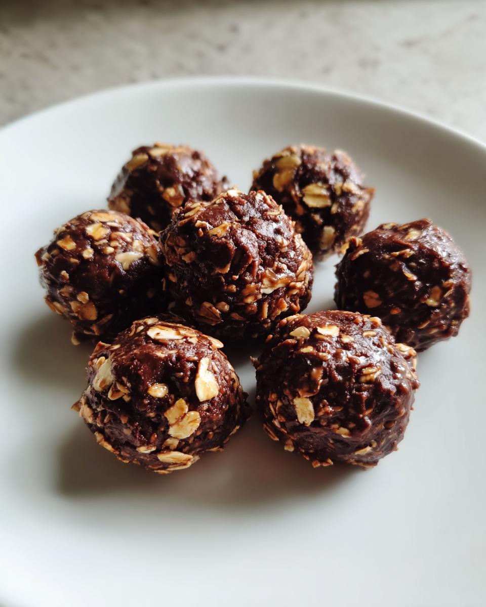 Seven chocolate hazelnut snack bites with oats on a white plate.