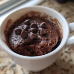 Close-up of a chocolate mug cake topped with chocolate chips in a white mug