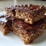 Close-up of chocolate topped no bake dessert bars stacked on a white plate