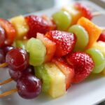 Close-up of vibrant fruit skewers with grapes, strawberries, pineapple, and melon for fruit snack recipes