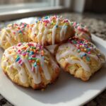 Easter sweet snack recipes featuring cookies with white icing and colorful sprinkles on a white plate.