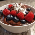 Bowl of easy chocolate desserts topped with raspberries, blueberries, whipped cream, and chocolate shavings.