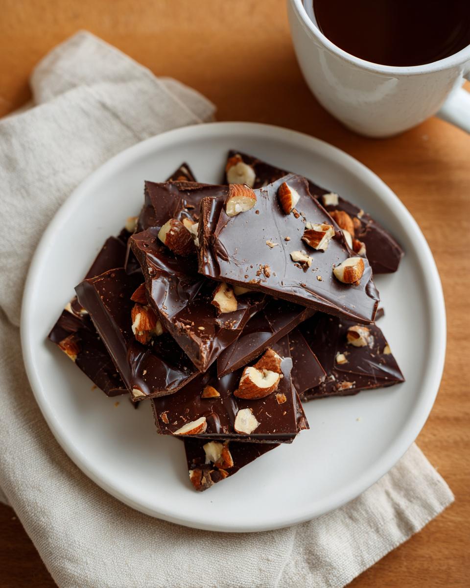 Plate of dark chocolate bark pieces topped with chopped almonds for easy chocolate snack ideas