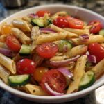 Bowl of easy pasta salads with penne, cherry tomatoes, cucumber, and red onion.