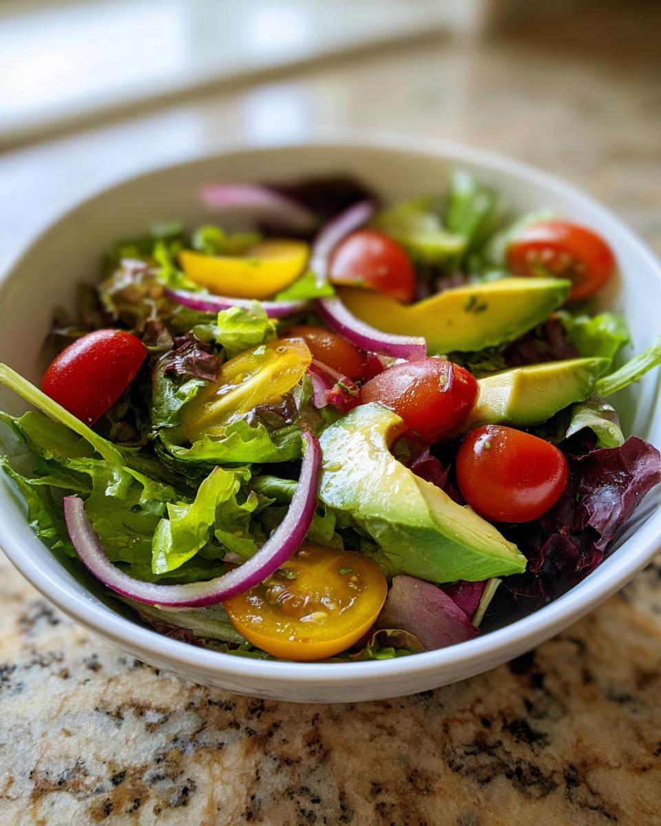 Bowl of fresh salad with avocado, cherry tomatoes, red onion, and mixed greens for light spring lunches.