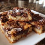 Close-up of homemade sweet snacks chocolate chip bars dusted with powdered sugar on a white plate.