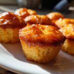 Close-up of golden honey butter cornbread bites glistening with honey on a white plate.