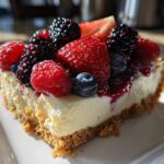 Slice of layered berry pudding dessert topped with strawberries, raspberries, blackberries, and blueberries.