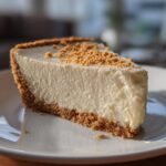 Close-up of a creamy no bake cheesecake dessert slice with graham cracker crust on white plate.