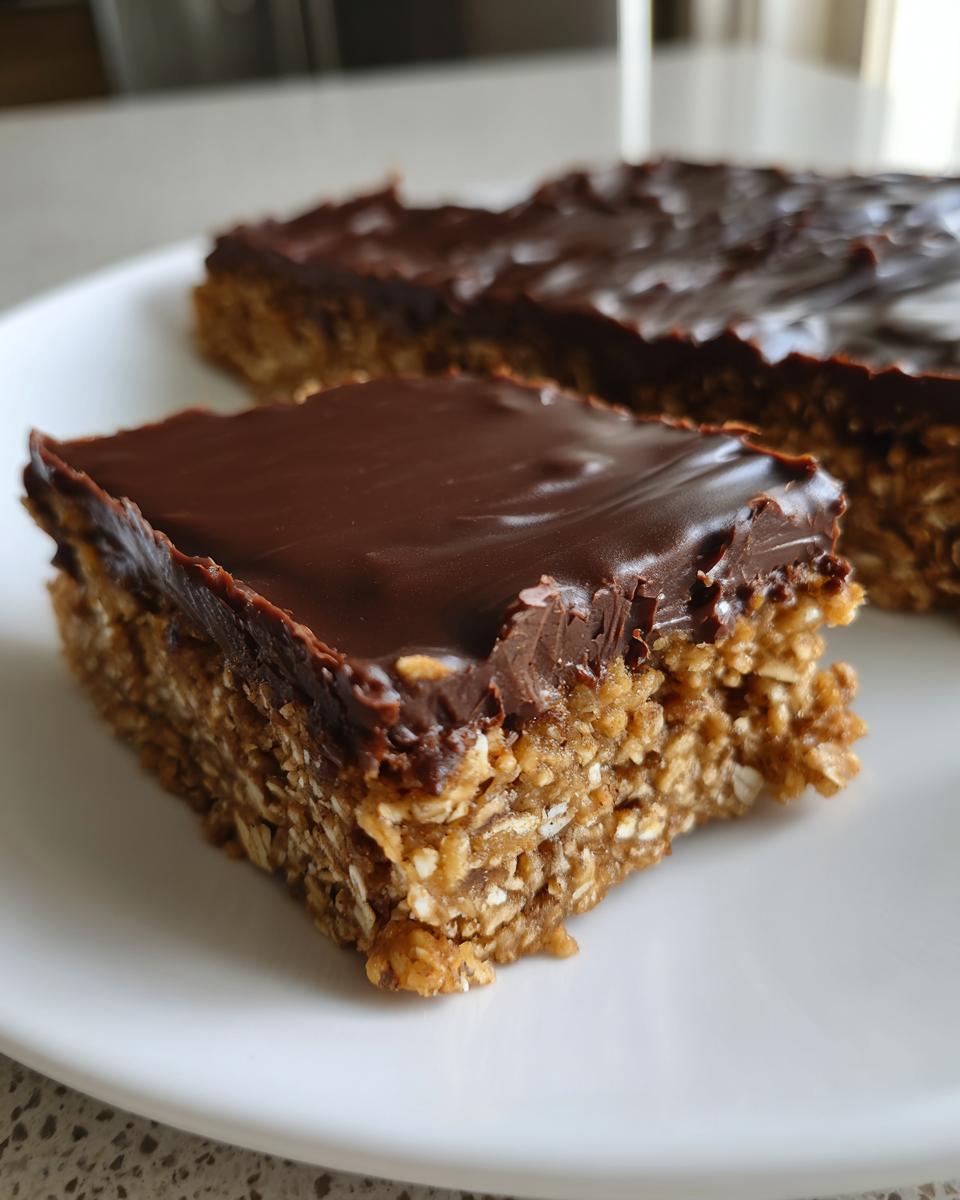 Close-up of a no bake dessert recipe bar with a chocolate layer on top and oat base.