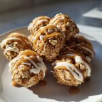 Close-up of peanut butter yogurt snack bites drizzled with caramel and white icing on a beige plate.