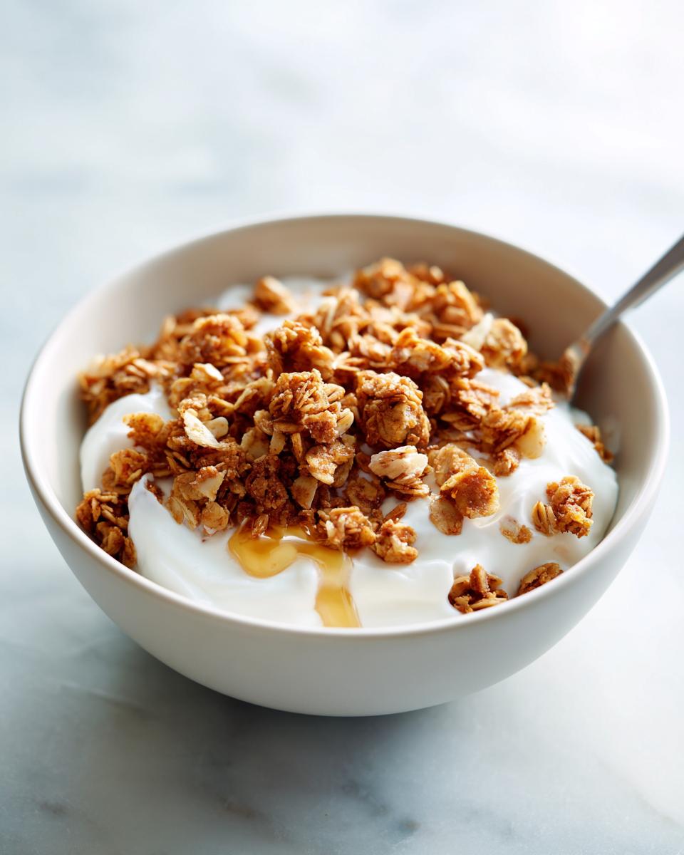 Bowl of yogurt topped with crunchy granola and honey drizzle, a quick snack recipe