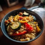Bowl of quinoa mixed with roasted zucchini, red and yellow bell peppers, and onions for easy vegetarian recipes