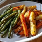 Plate of roasted green beans and colorful carrots, perfect Easter side dishes.