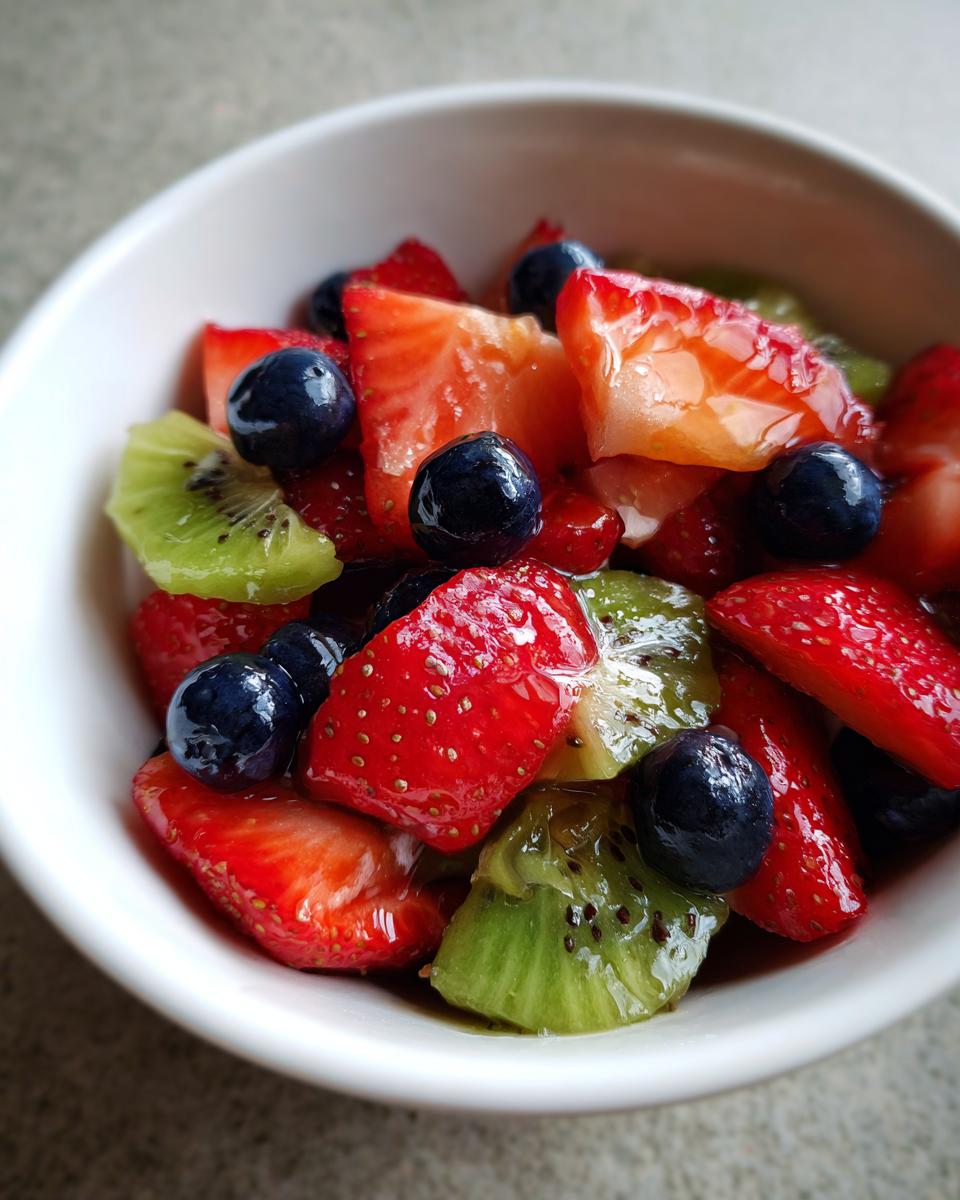 Bowl of fresh spring fruit desserts with strawberries, blueberries, and kiwi slices.