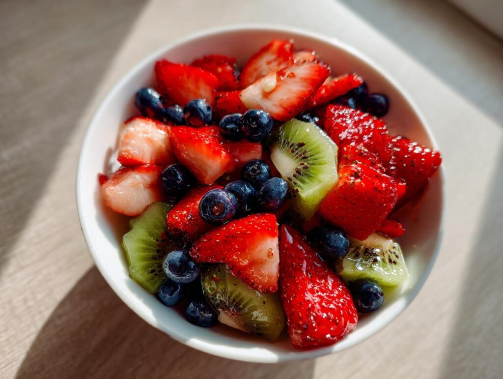 Bowl of spring fruit desserts featuring sliced strawberries, kiwi, and blueberries.