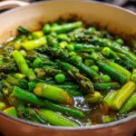 Close-up of a spring one pot meal with asparagus and peas simmering in broth.