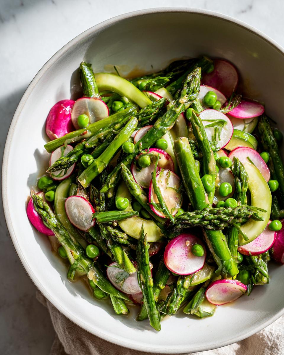 Bowl of spring vegetable side dishes featuring asparagus, radishes, peas, and zucchini slices.