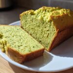 Sliced loaf of green avocado protein bread on a white plate