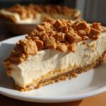 Close-up of a slice of Butterfinger Pie with creamy filling and crushed Butterfinger candy on top.