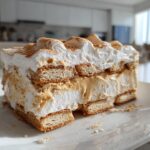 Close-up of a creamy peanut butter icebox cake slice with layers of whipped topping and cookies.