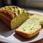 Loaf of keto avocado bread with two slices on a white plate in natural light